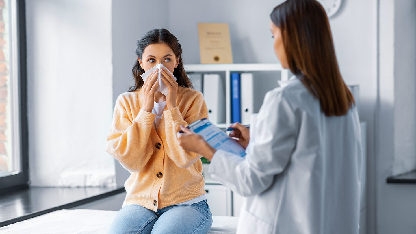 Një grua me grip duke u ekzaminuar nga një mjek.
