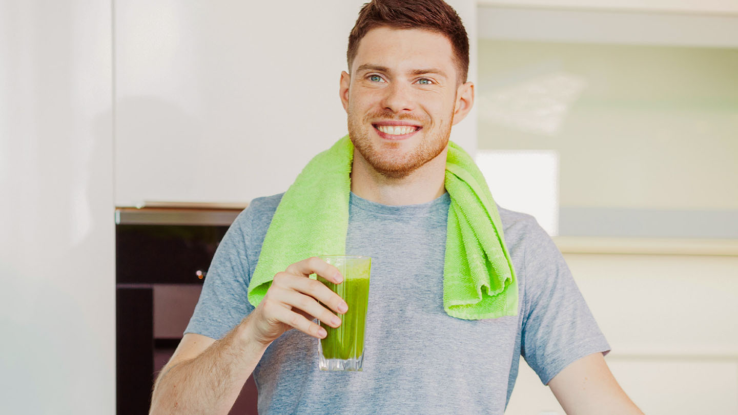 Një burrë shijon një smoothie të shëndetshëm jeshil.
