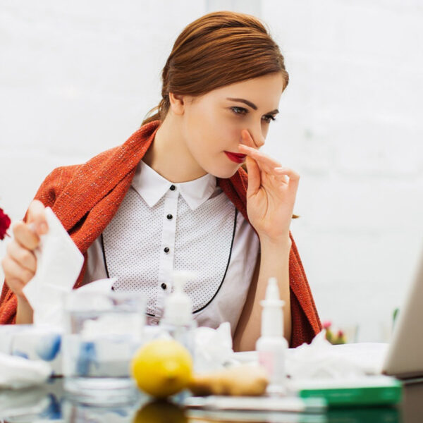 Grua e sëmurë me të ftohtë në zyrë.
