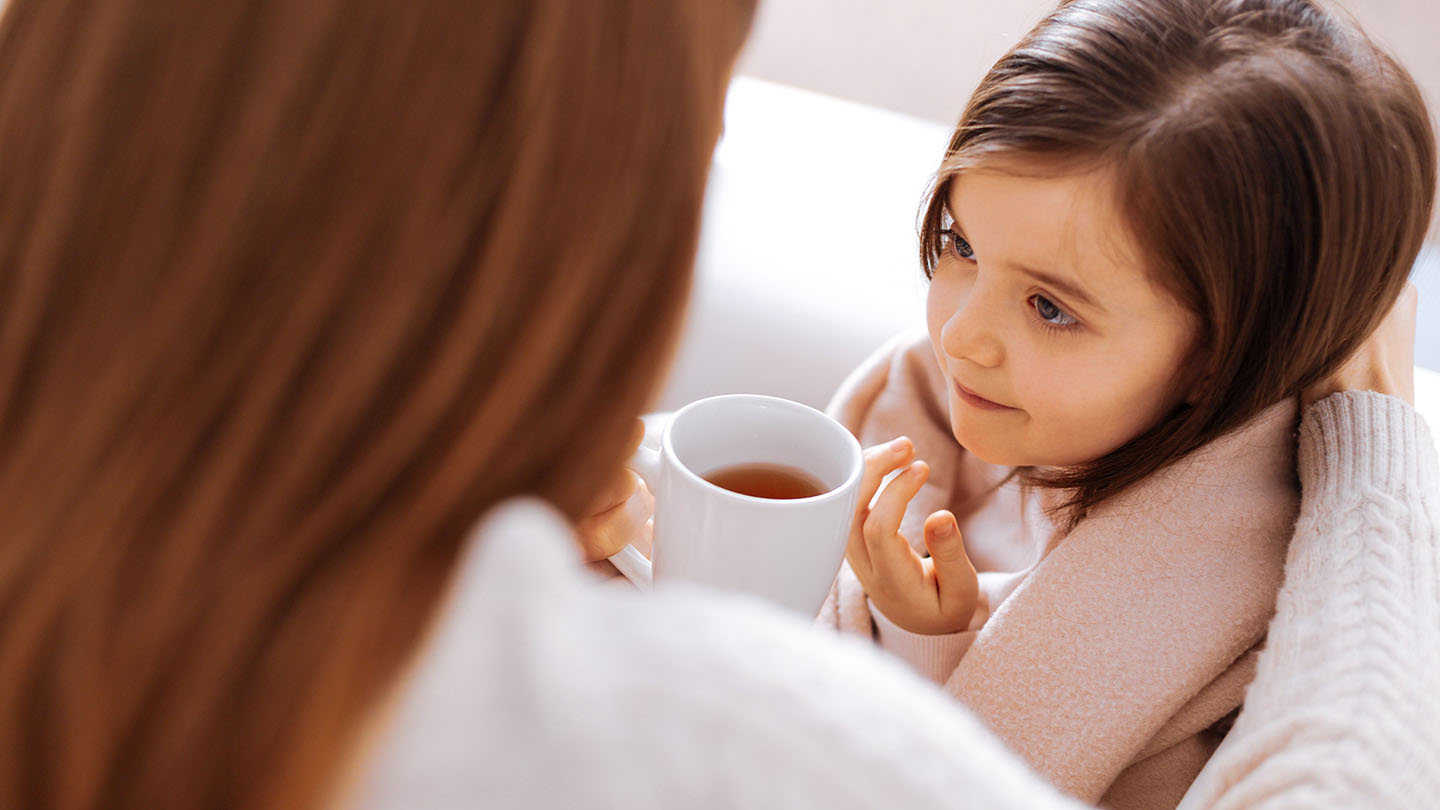 Një nënë i ofron çaj vajzës së saj, e cila është e sëmurë me grip.
