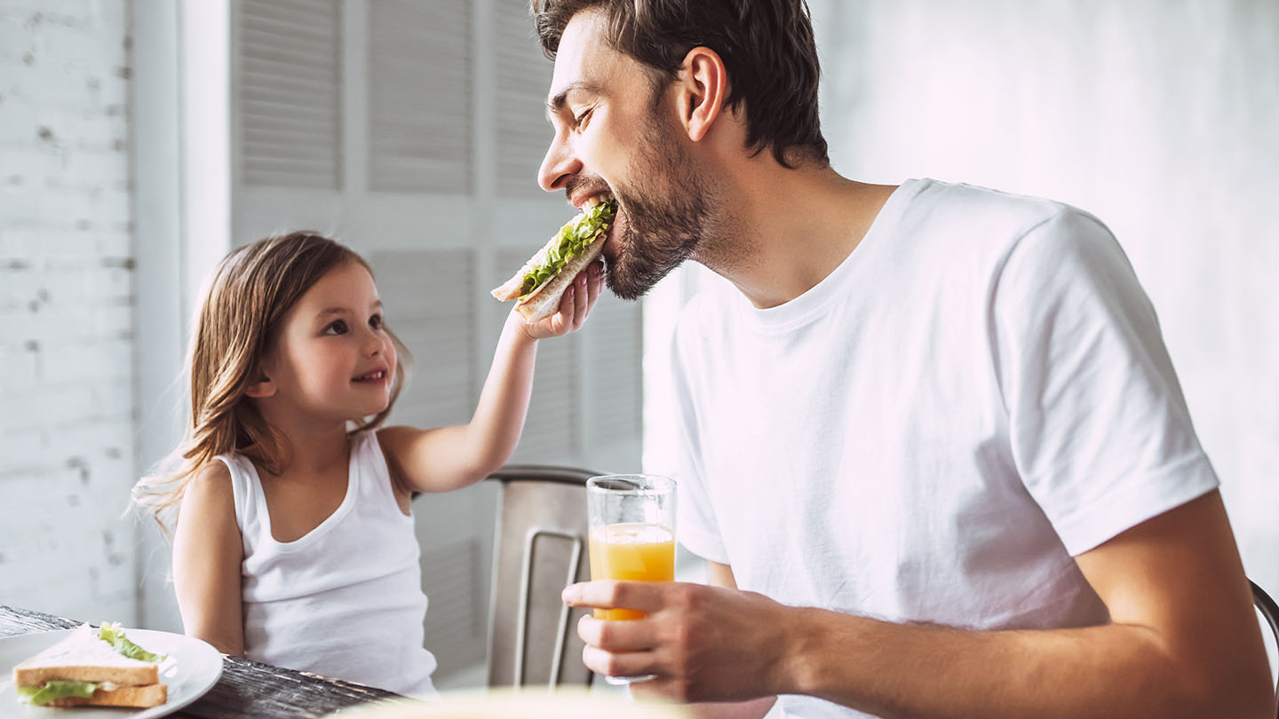 Babai dhe fëmija duke shijuar një sanduiç.
